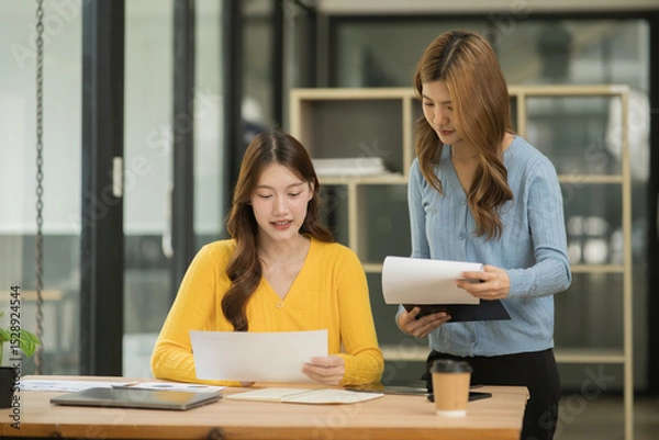 Fototapeta Asian businesswoman sitting in a meeting, talking about a document and chart placed on the table.