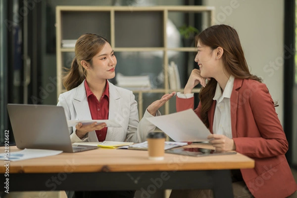 Fototapeta Asian businesswoman sitting in a meeting, talking about a document and chart placed on the table.