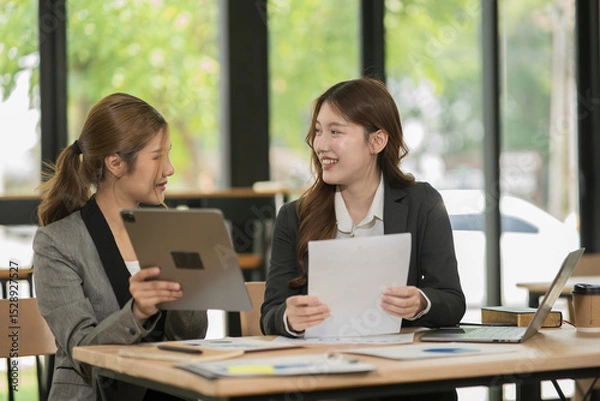 Fototapeta Asian businesswoman sitting in a meeting, talking about a document and chart placed on the table.