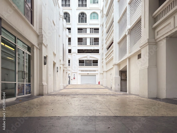 Fototapeta Empty alleyway in a commercial building with white walls and glass doors