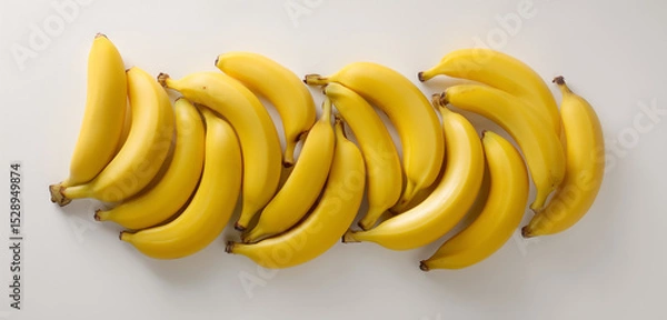 Obraz A bunch of bananas with bright yellow skin, arranged artistically on a white surface