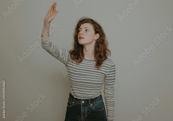 Fototapeta Full-Body Portrait of a Young Woman in Jeans and Striped Top – Artistic Pose with Open Palm and Raised Hand, White Background, Studio Shot, High-Resolution Fashion and Lifestyle Photography
