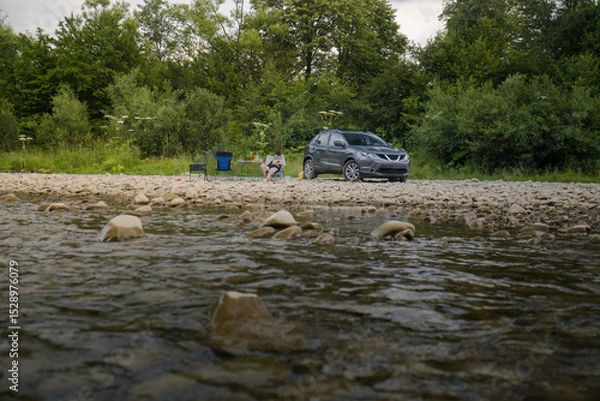 Fototapeta Camping by the River with SUV and Campfire