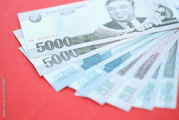 Fototapeta North Korean won money bills in big amount lies on red color table close up