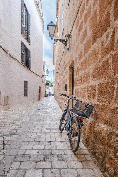 Fototapeta Quaint Cobblestone Alley In Ciutadella Old Town With A Bicycle And Traditional Architecture. Menorcan Street Scene, Spanish Island Life, Historic Charm