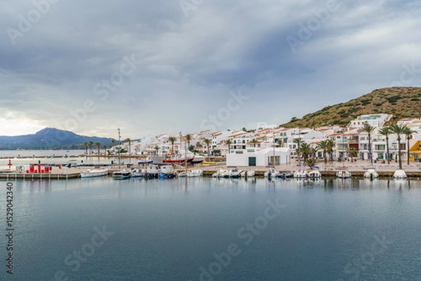Fototapeta Charming Mediterranean Coastal Village With White Buildings And Boats. Menorcan Architecture, Balearic Islands, Spanish Island Life, Travel Destination