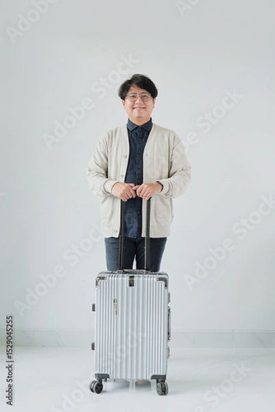 Fototapeta A man is standing in front of a suitcase