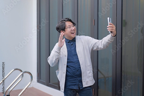 Fototapeta A man is taking a selfie with his cell phone