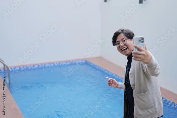 Fototapeta A man is taking a picture of himself in a pool