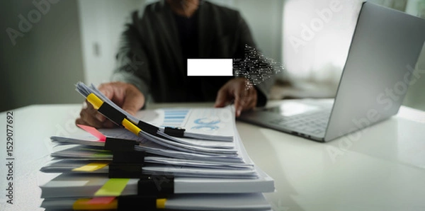 Obraz Digital Transformation person working desk with laptop and large stack of documents, holding pen, modern office environment, with focus paperwork