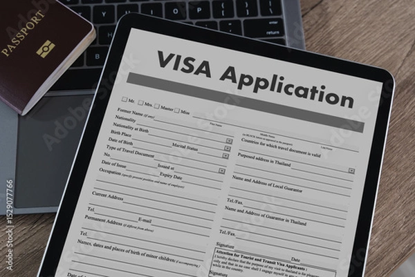 Obraz Visa application digital tablet displaying visa application form with passport and laptop background, wooden surface, representing travel