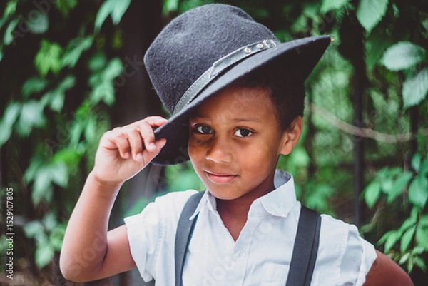 Fototapeta boy dressed in the style of the 20s lifts his hat holding it by the brim