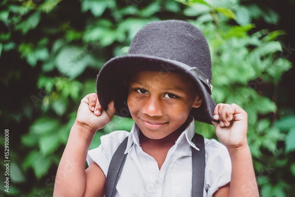 Fototapeta a boy dressed in the style of the 20s pulls his hat down over his ears, holding the brim with both hands