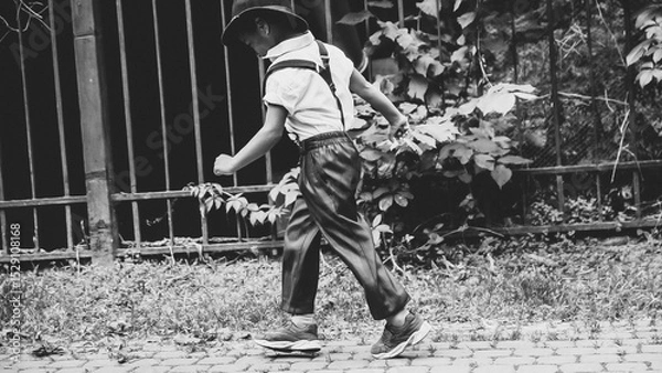 Fototapeta A boy dressed in the style of the 20s jumps down the street side view
