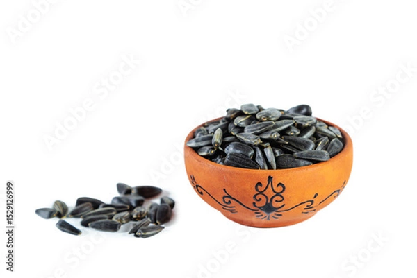 Fototapeta Heap of sunflower seeds in clay bowl isolated on white background.