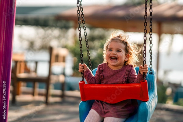 Fototapeta portrait of a adorable little girl laughing when playing a swing