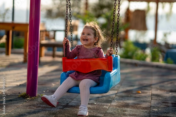 Fototapeta Portrait of a adorable little girl laughing when playing a swing