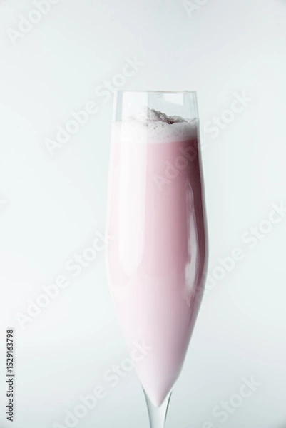 Fototapeta A tall glass with a frothy pink smoothie against a clean white background. The drink’s creamy texture and vibrant color make it look refreshing and inviting, perfect for summer or dessert concepts