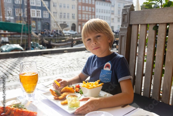 Obraz Family with children, having lunch in a restaurant in Coppenhagen, eating local fish and lobster thermidor with salad and fries