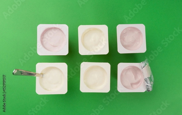 Obraz Yogurt cups set, pink and yellow fruit yoghurt in plastic pots, milk pudding container with spoon