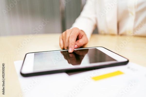 Obraz Close-up of a business professional using a digital tablet on a desk, focusing on touchscreen interaction, digital workflow, and paperless productivity in a modern office setting.
