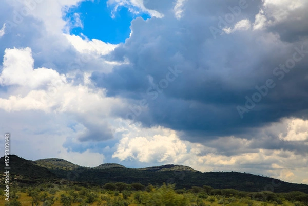 Fototapeta Beautiful cloud formation in the African landscape with Mountain range in the Background. Panoramic view.