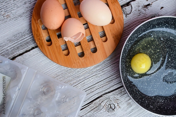 Obraz Making breakfast - frying eggs in the small pan.