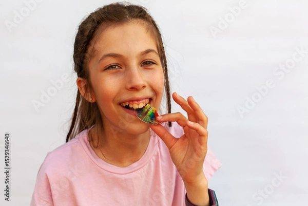 Fototapeta Happy girl in pink t-shirt putting orthodontic plate on teeth with uneven teeth, malocclusion on white background. Concept orthodontic treatment