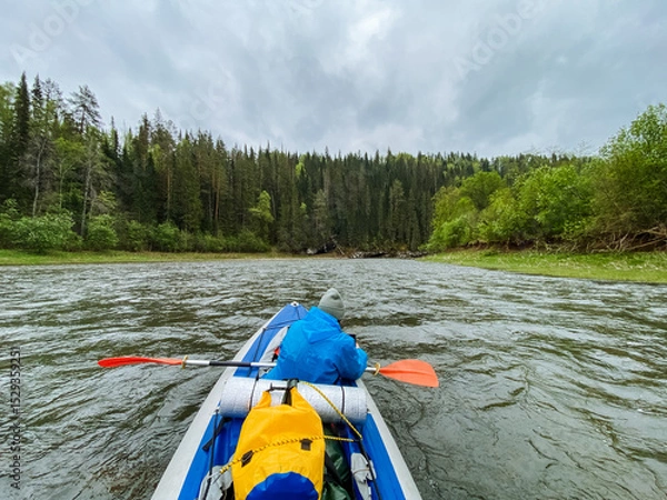 Obraz A person is actively paddling a kayak down a winding river, enjoying the serene surroundings and the thrill of navigating the water. Its a wonderful outdoor recreation experience