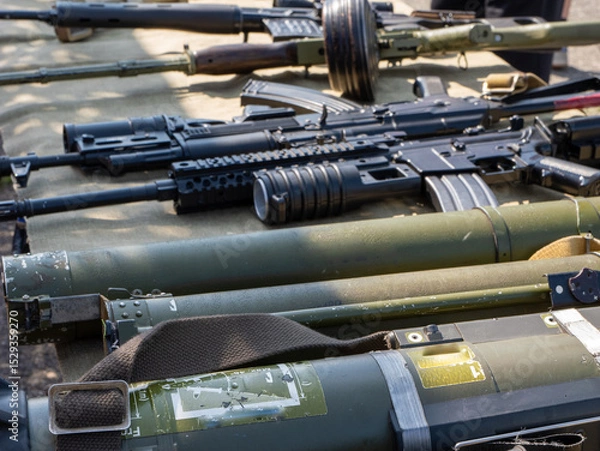 Fototapeta A bunch of guns are lined up on a table