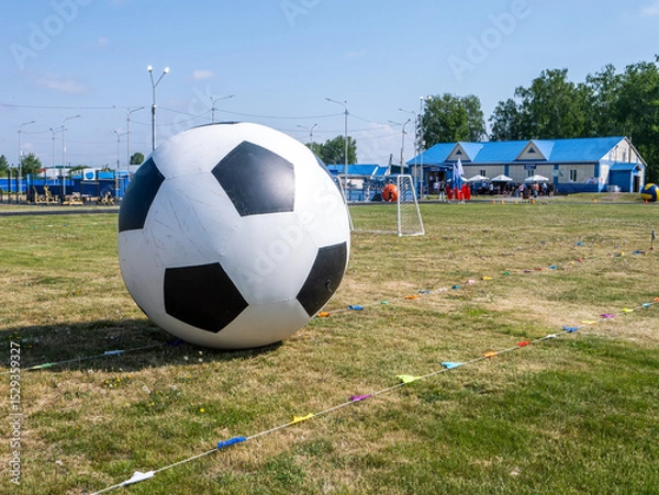 Fototapeta A large inflatable soccer ball sits on a field