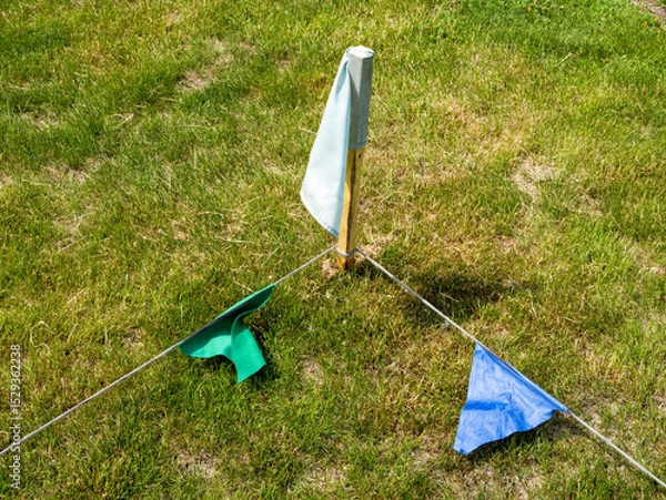 Fototapeta A green, blue and white flag is on a grassy field