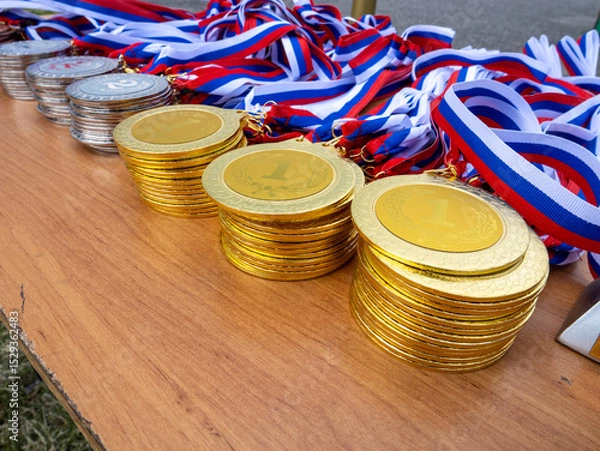 Fototapeta A table with a pile of gold medals and a ribbon
