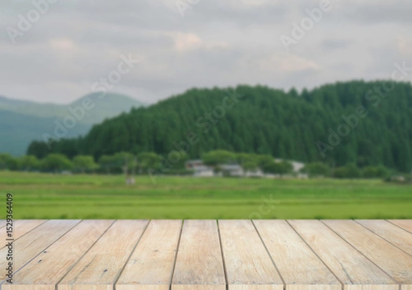 Fototapeta Wooden table top on blur  field and mountain background in daytime.For montage product display or design key visual layout.View of copy space.