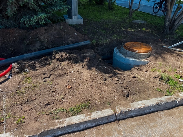 Obraz A manhole cover is being installed by the roadside for access to essential underground utilities and drainage systems vital for infrastructure maintenance and improvement