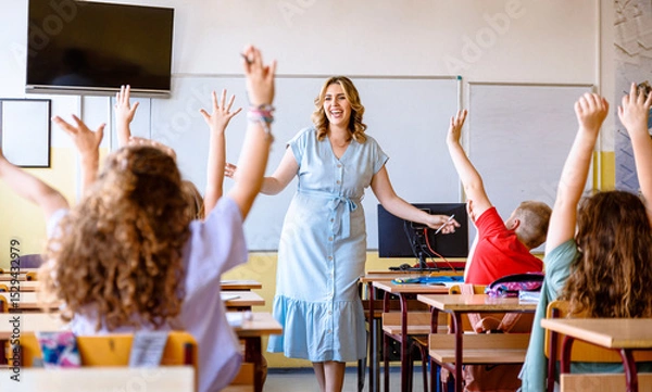 Obraz Schoolchildren raising hands to answer teacher's question during class in classroom.