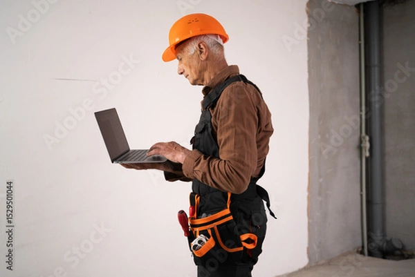 Obraz professional male builder showing construction on new house. civil engineer in safety helmet using laptop computer