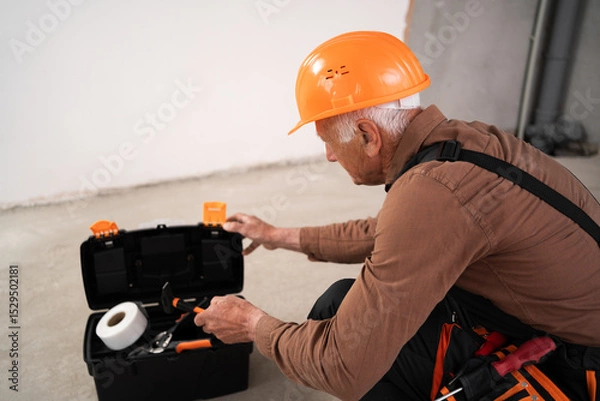 Obraz Elderly civil engineer or builder opening toolbox making house repair working on home interior design