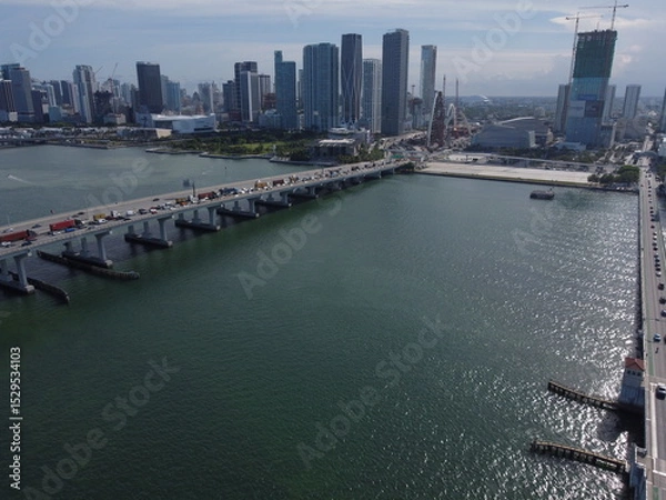 Fototapeta Wide daytime drone photo of Biscayne Bay facing Midtown and Downtown Miami, with skyline and blue waters under clear skies.
