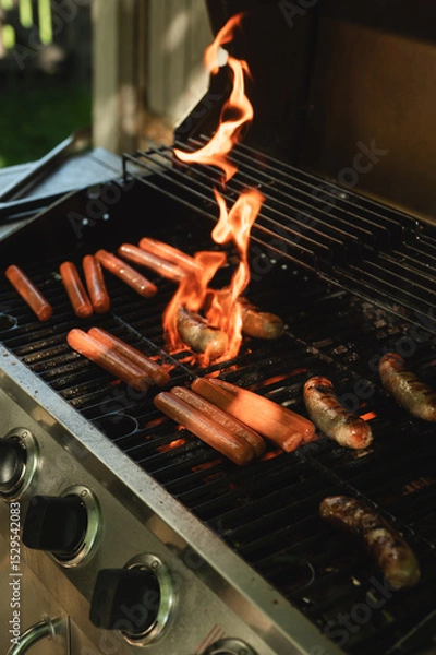 Fototapeta Hot Dogs and Sausages Flaming on a Backyard Barbecue Grill