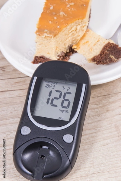 Fototapeta Glucometer and portion of cheesecake. Measuring and checking sugar level during diabetes