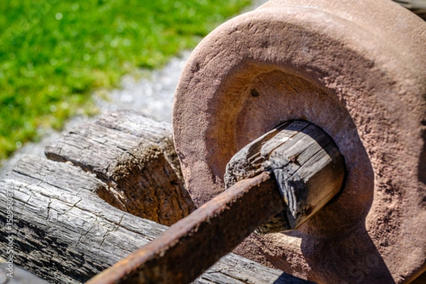 Fototapeta Historical stone wheel used for grinding grains in a rustic farming setting during daylight hours in an outdoor environment