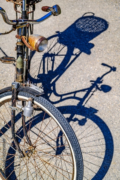 Fototapeta Vintage blue bicycle leaning against a colorful wall in bright sunlight during afternoon hours in an urban setting