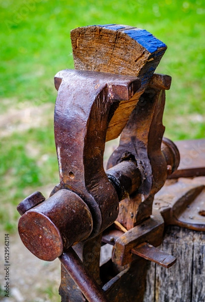 Fototapeta Vintage woodworking vise showcased in a rustic workshop setting with tools and cabinets arranged behind it