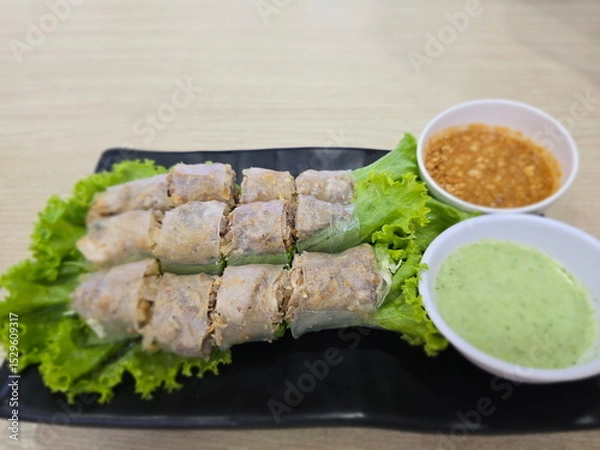 Obraz Vietnamese Spring rolls cut into bite-sized pieces and arrange on bed of salad greens. Serve with seafood sauce, sweet sauce. Rice paper wrapped with minced pork, swineskin, herbs rolled all together
