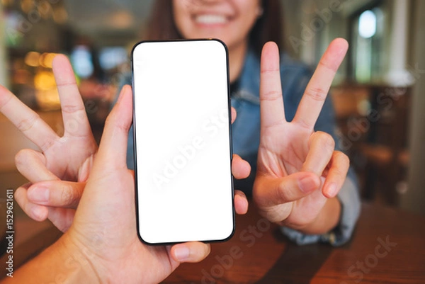 Fototapeta Mockup image of a man holding mobile phone with blank screen with a cheerful woman in background