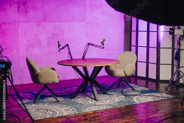 Fototapeta Podcast setup featuring microphones and headphones in a modern studio with a vibrant background