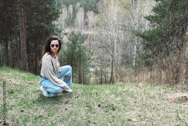 Obraz Girl with glasses grey knitted jacket on a forest background.