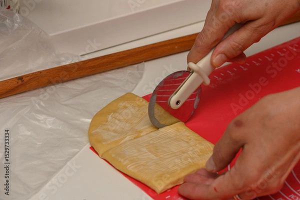 Obraz Woman slices soft dough into pieces for Parker House buns in a home kitchen.