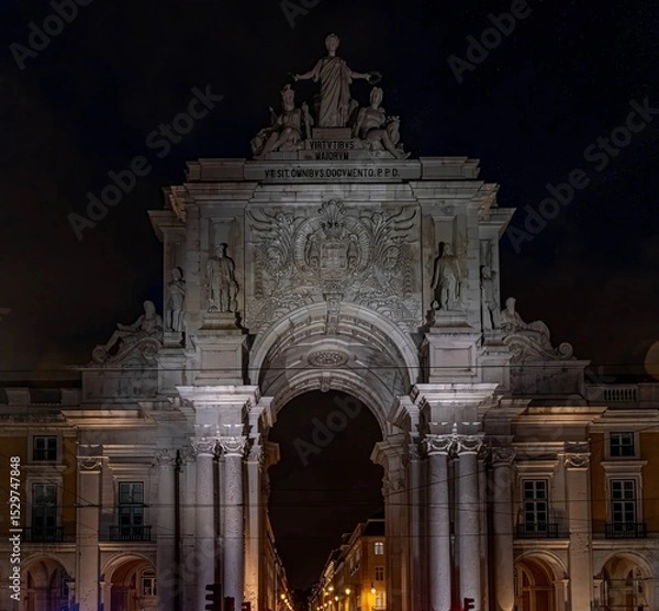 Obraz Night shot of the illuminated Arco da Rua Augusta in Lisbon, an 18th-century ornate triumphal arch with carved figures and views of the city centre.